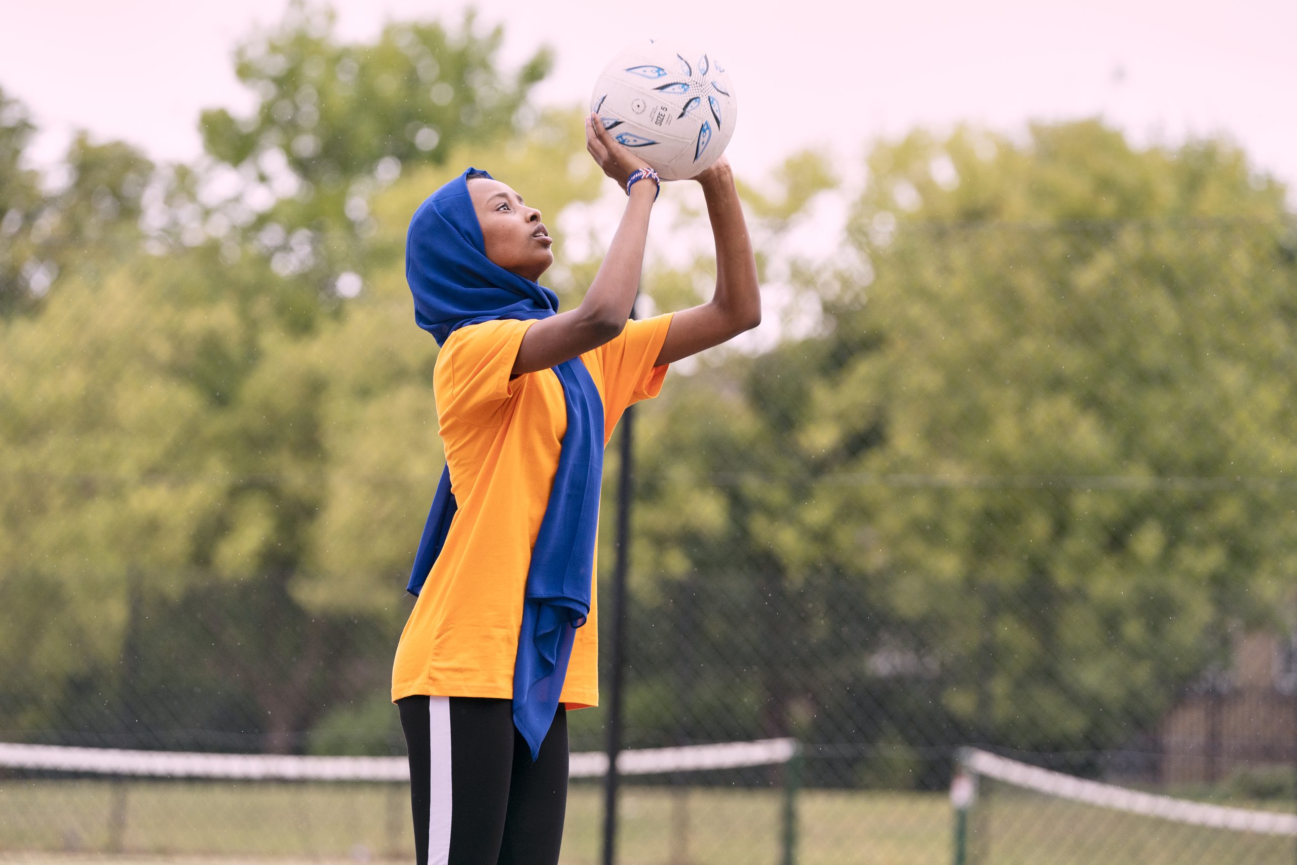 A muslim teenage girl playing netball
