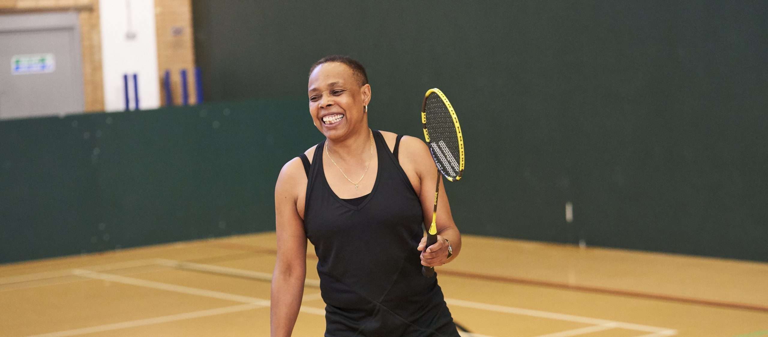A mixed race woman aged 45-55 playing badminton