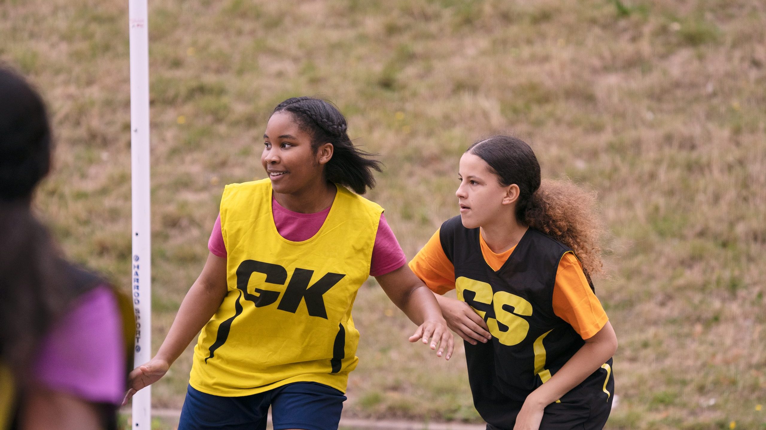Two young black teenage girls playing netball