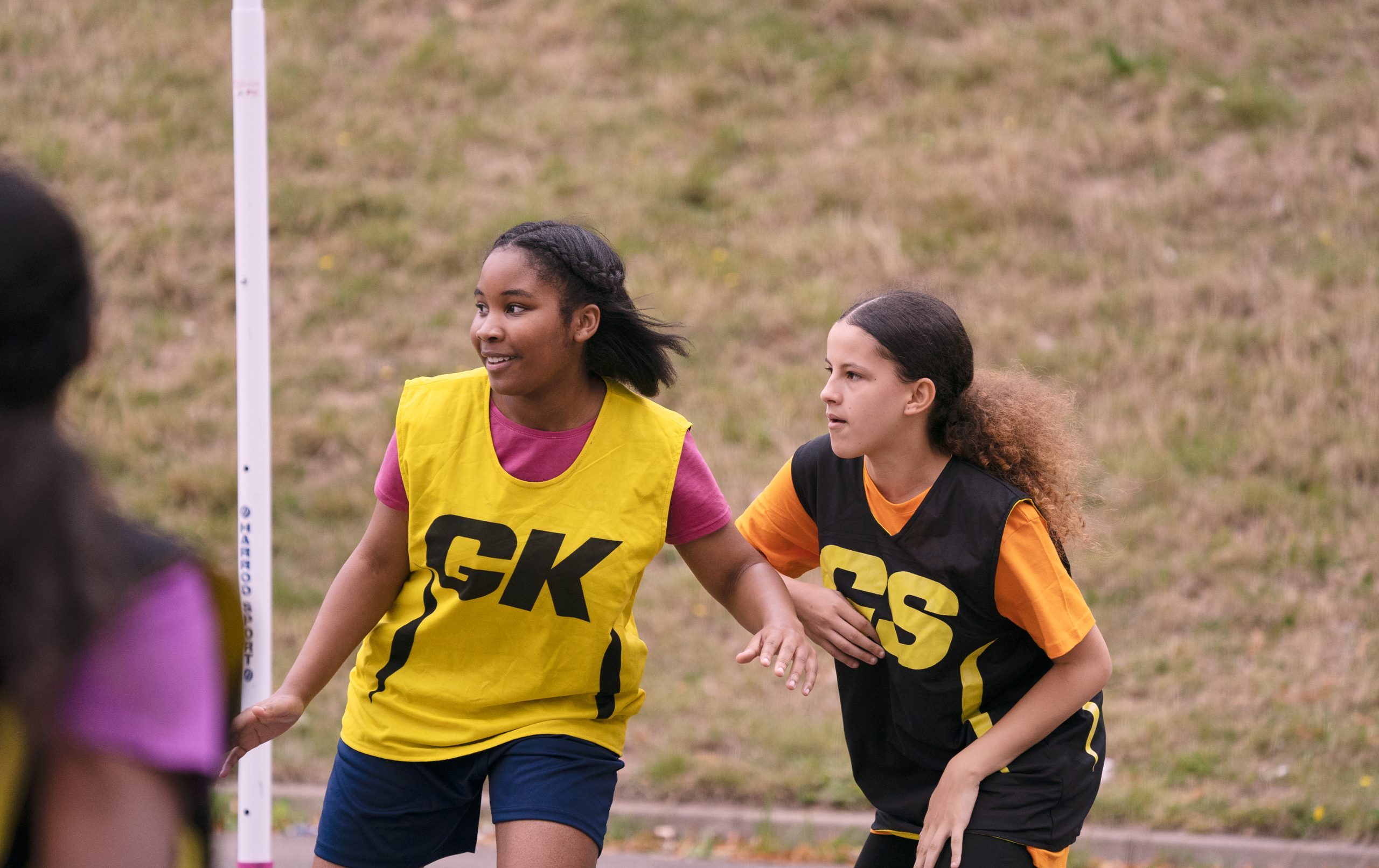 Two young black teenage girls playing netball