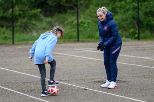 Young girl aged 8-12 with visual impairment being coached in football