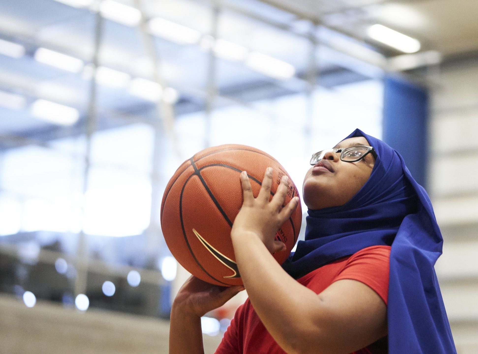 Teenage girl wearing headscarf shooting the ball in basketball