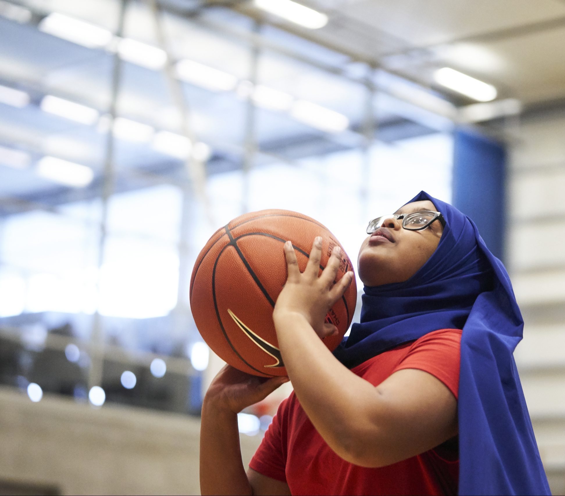 Teenage girl wearing headscarf shooting the ball in basketball