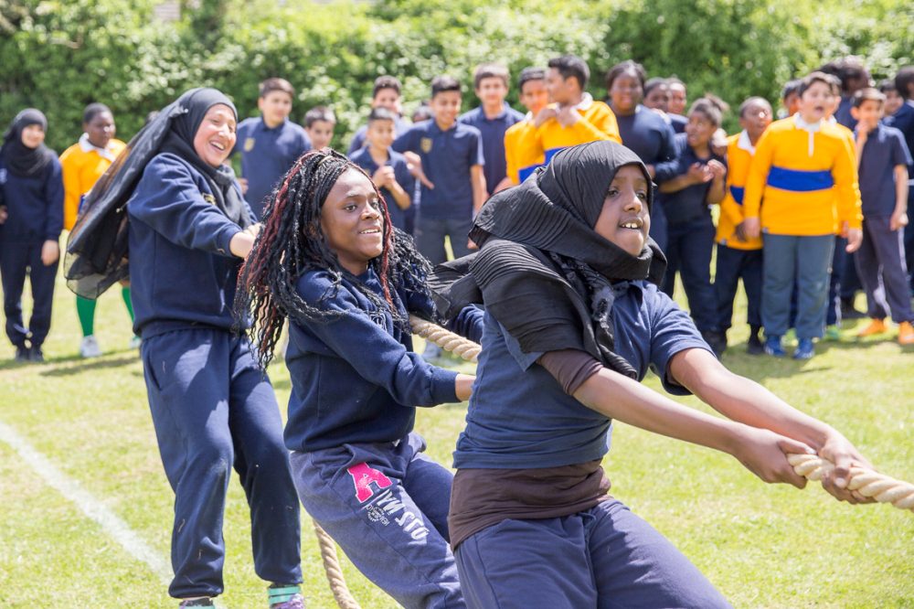 Teen girls from different backgrounds playing tug of war