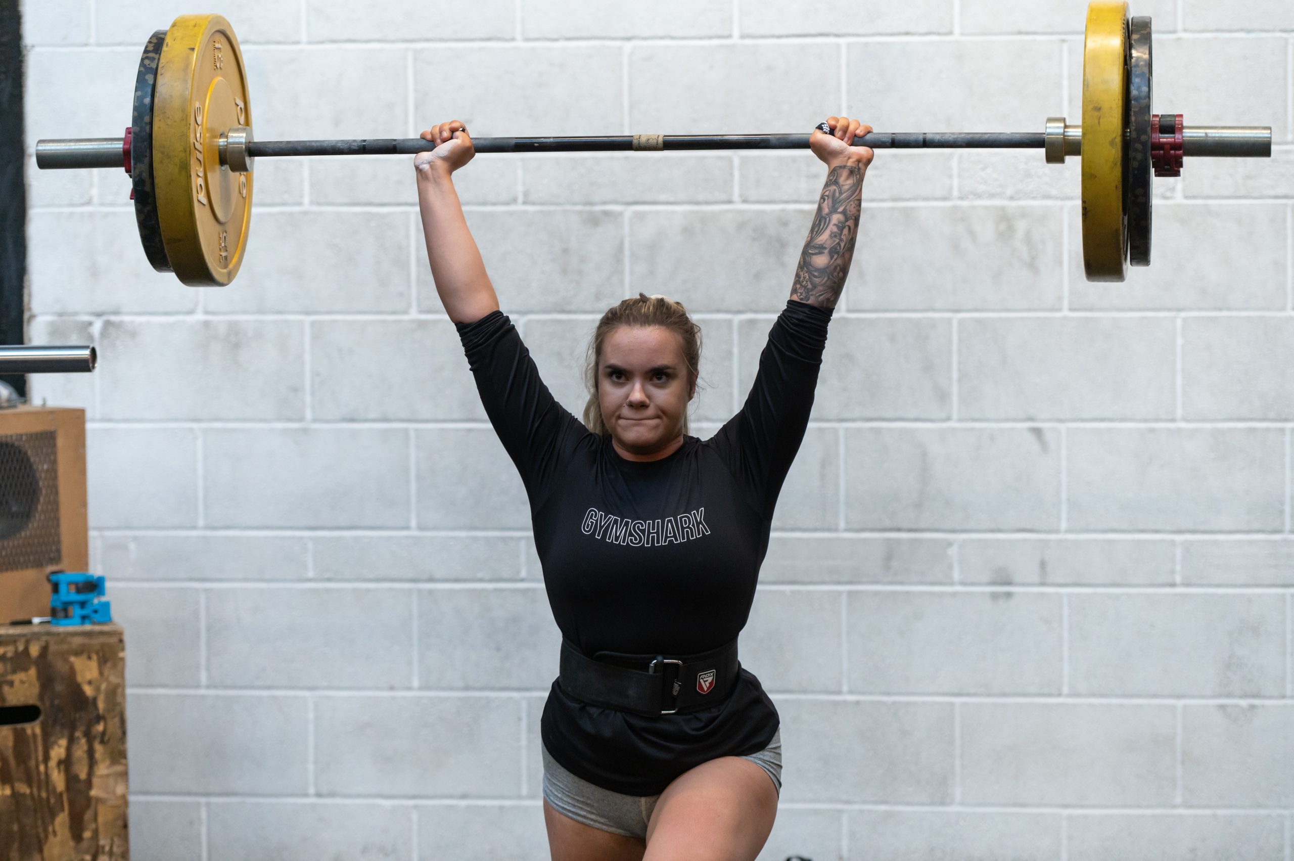 White woman aged 25-35 lifting a bar weight above her head