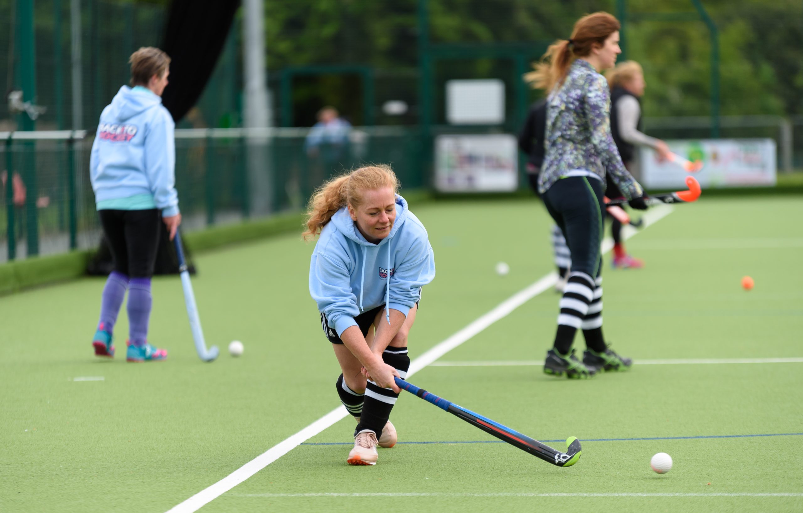 A white woman aged 35-45 playing hockey with her local club