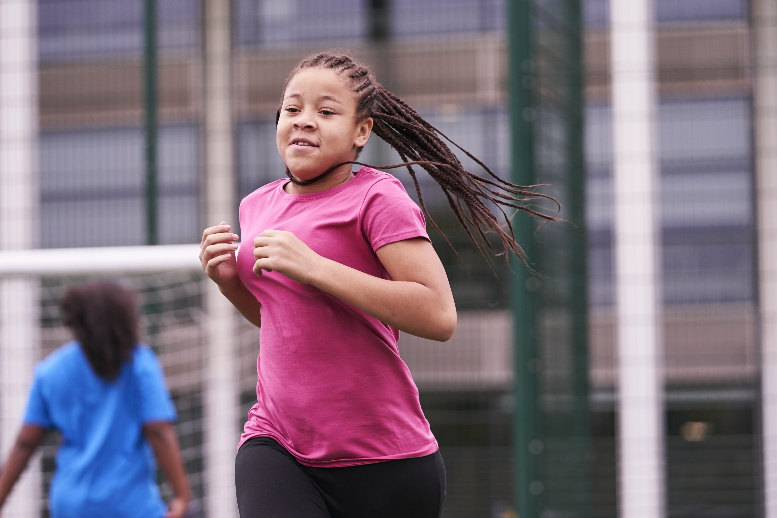 A black teenage girl with braided hair running