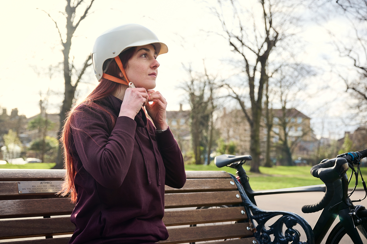 White woman aged 34 fastening her cycling helmet