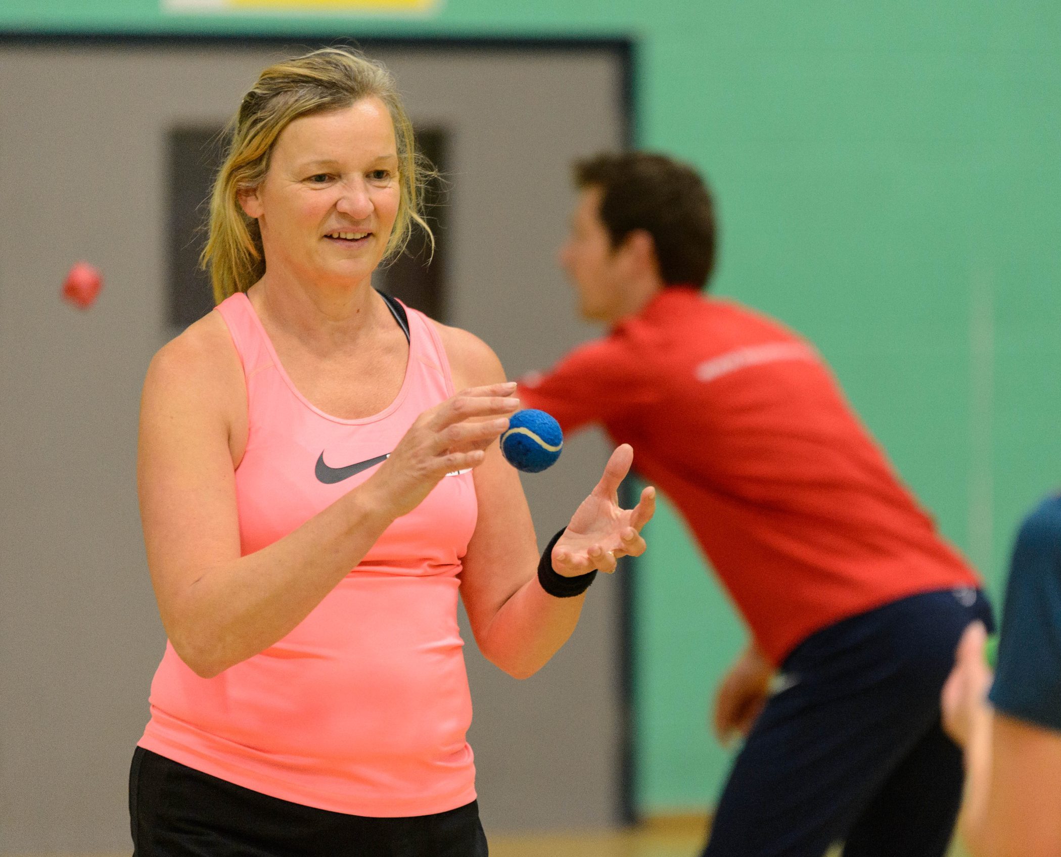 White woman aged 40-50 catching a tennis ball