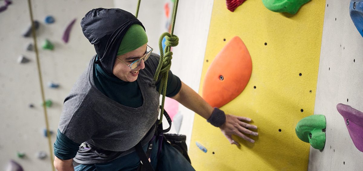 A Muslim para climber smiling while while tied into a rope