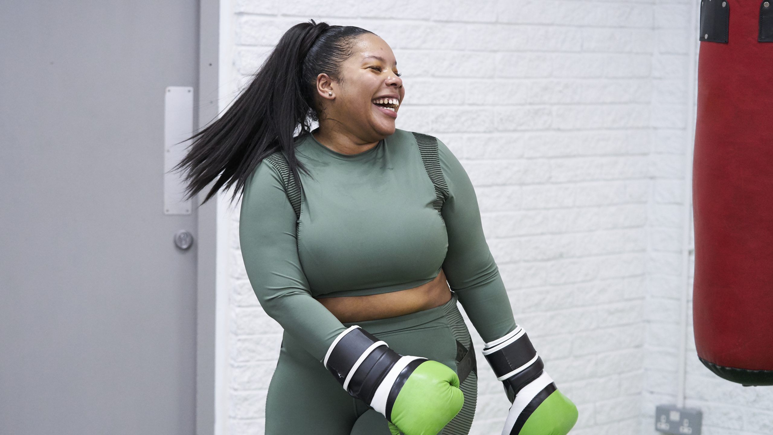 A black woman aged 25-30 laughing while practicing boxing