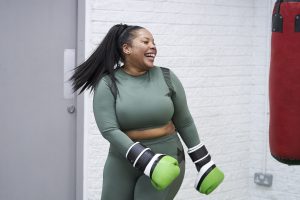 A black woman aged 25-30 laughing while practicing boxing