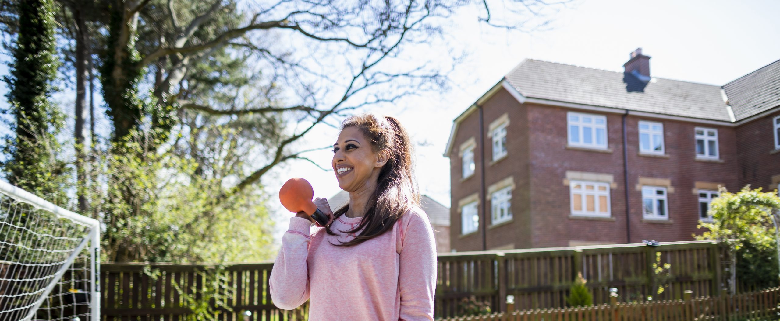 Shazia, a south Asian woman aged 45-55 lifting weights in her garden