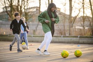 A young muslim girl playing football in the school playground