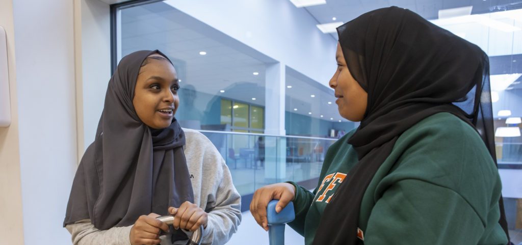 Two Muslim teenage girls chatting at the gym