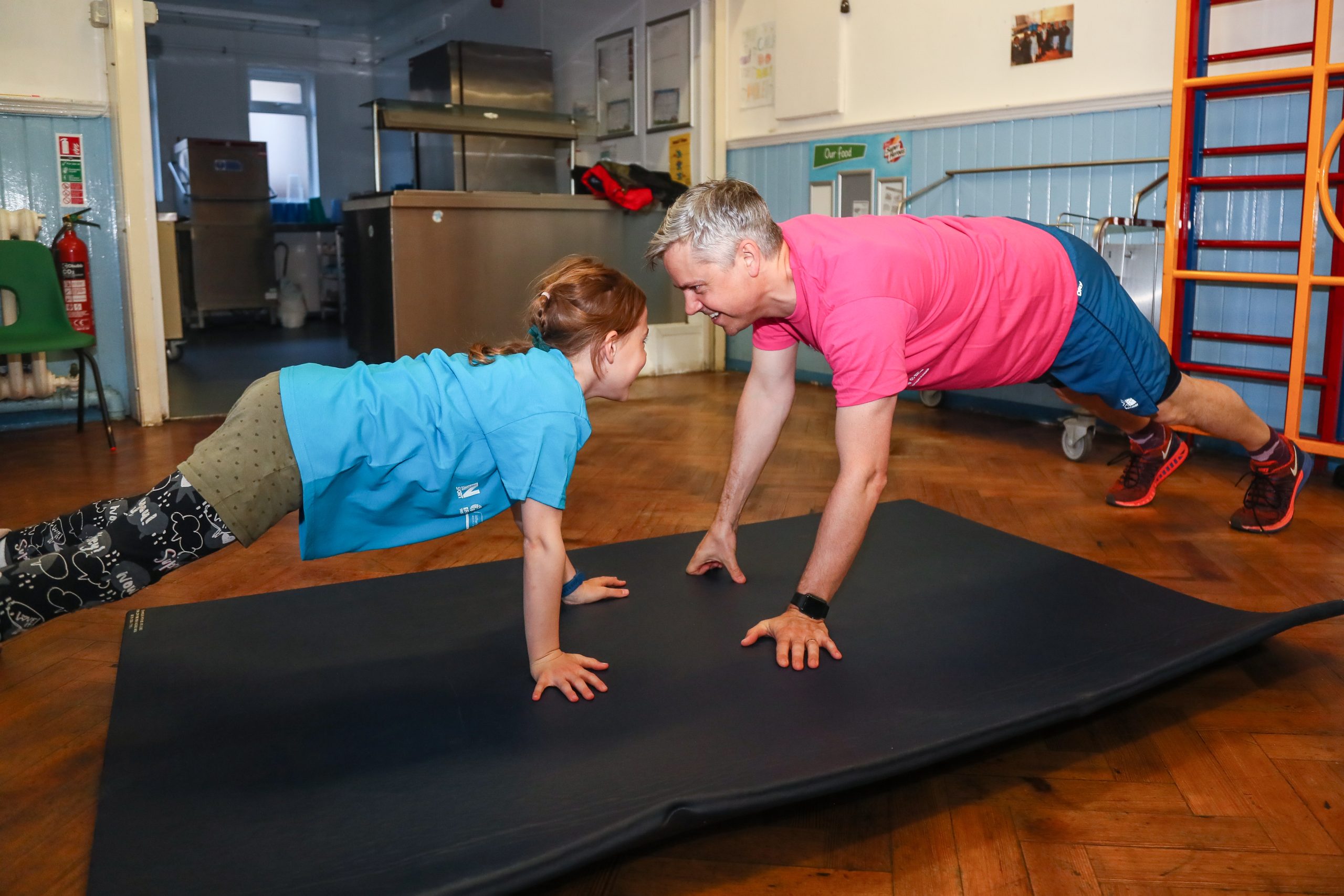A dad and his daughter doing the plank facing each other