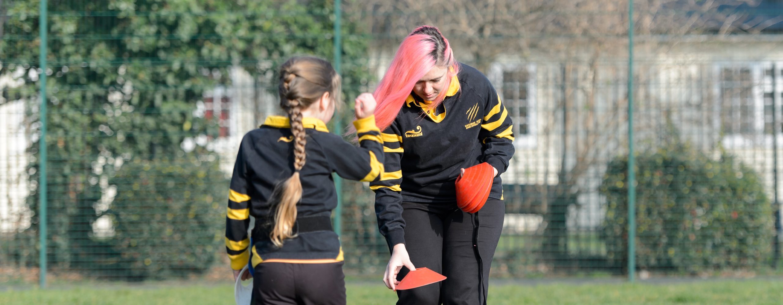 A young girl and a volunteer setting up the pitch for a rugby game