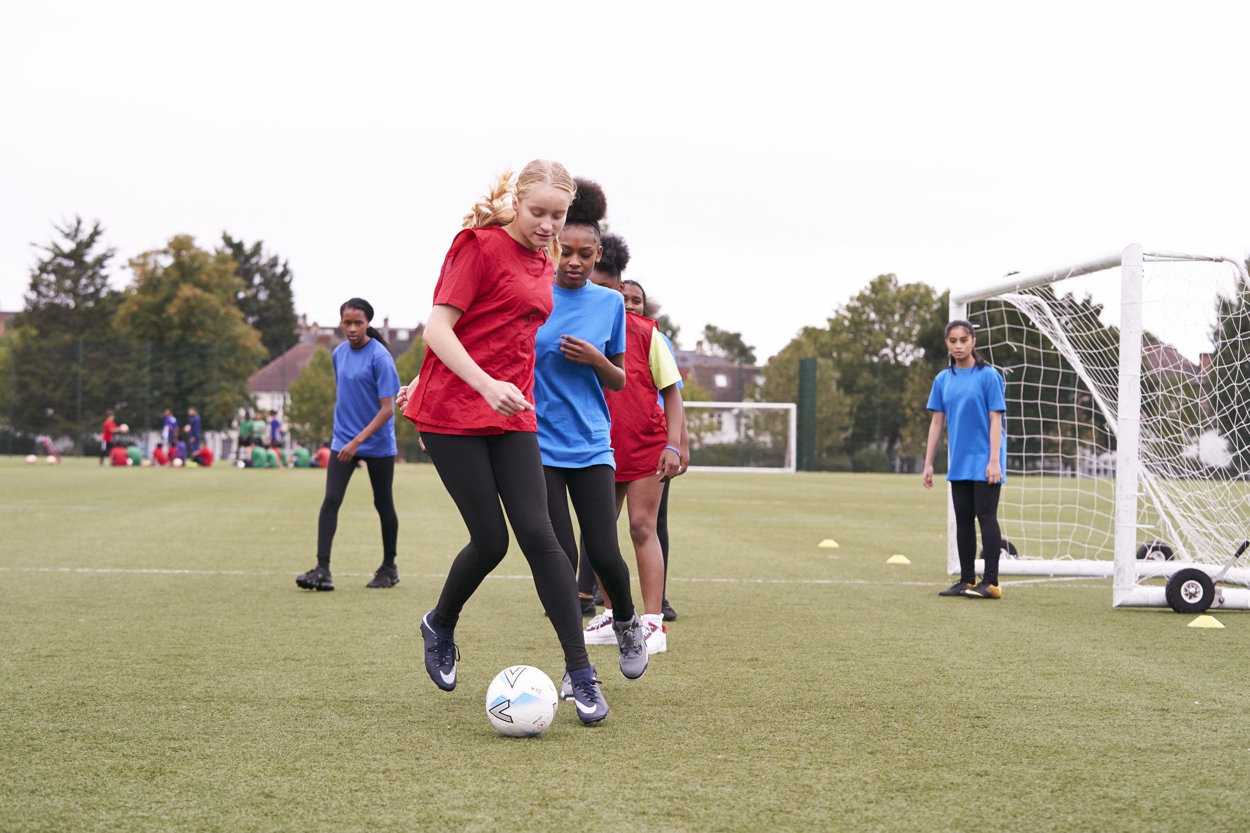 Teenage girls playing football on the school field
