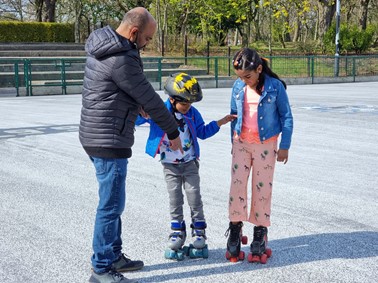 Father with daughter and son, helping them to roller skate