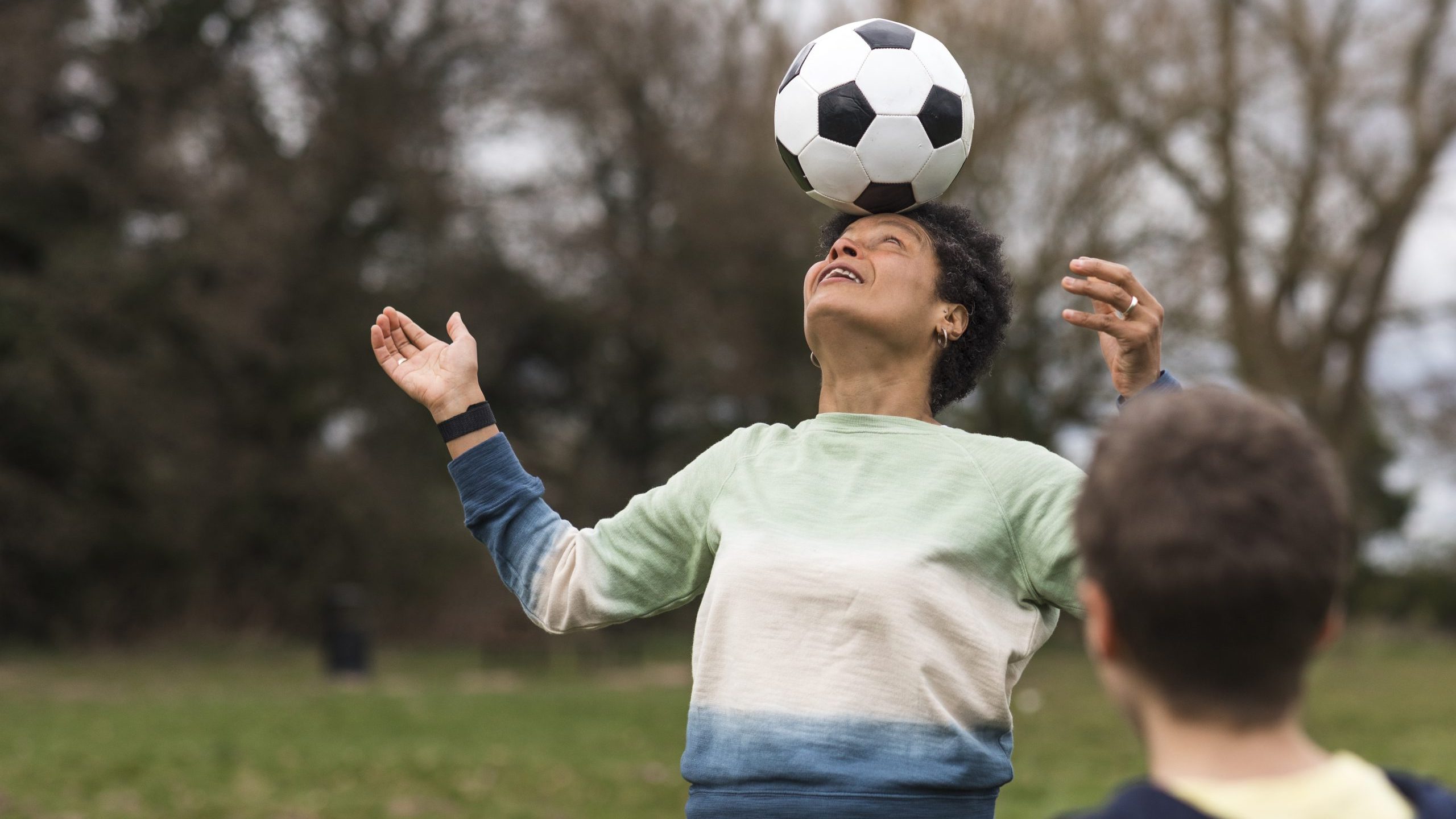 Black woman aged 45-55 playing football with her sun