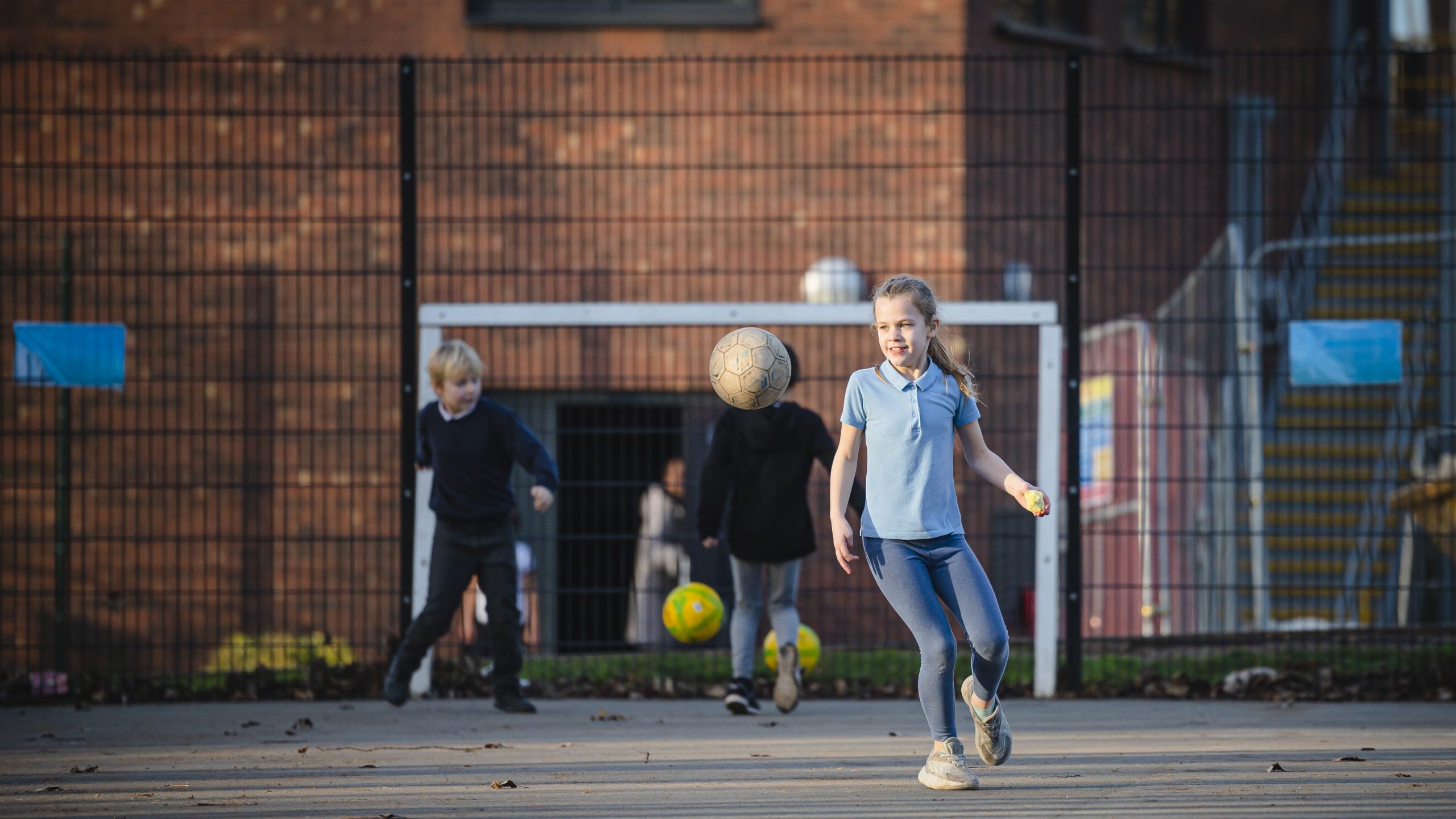 Young blonde girl playing football at school