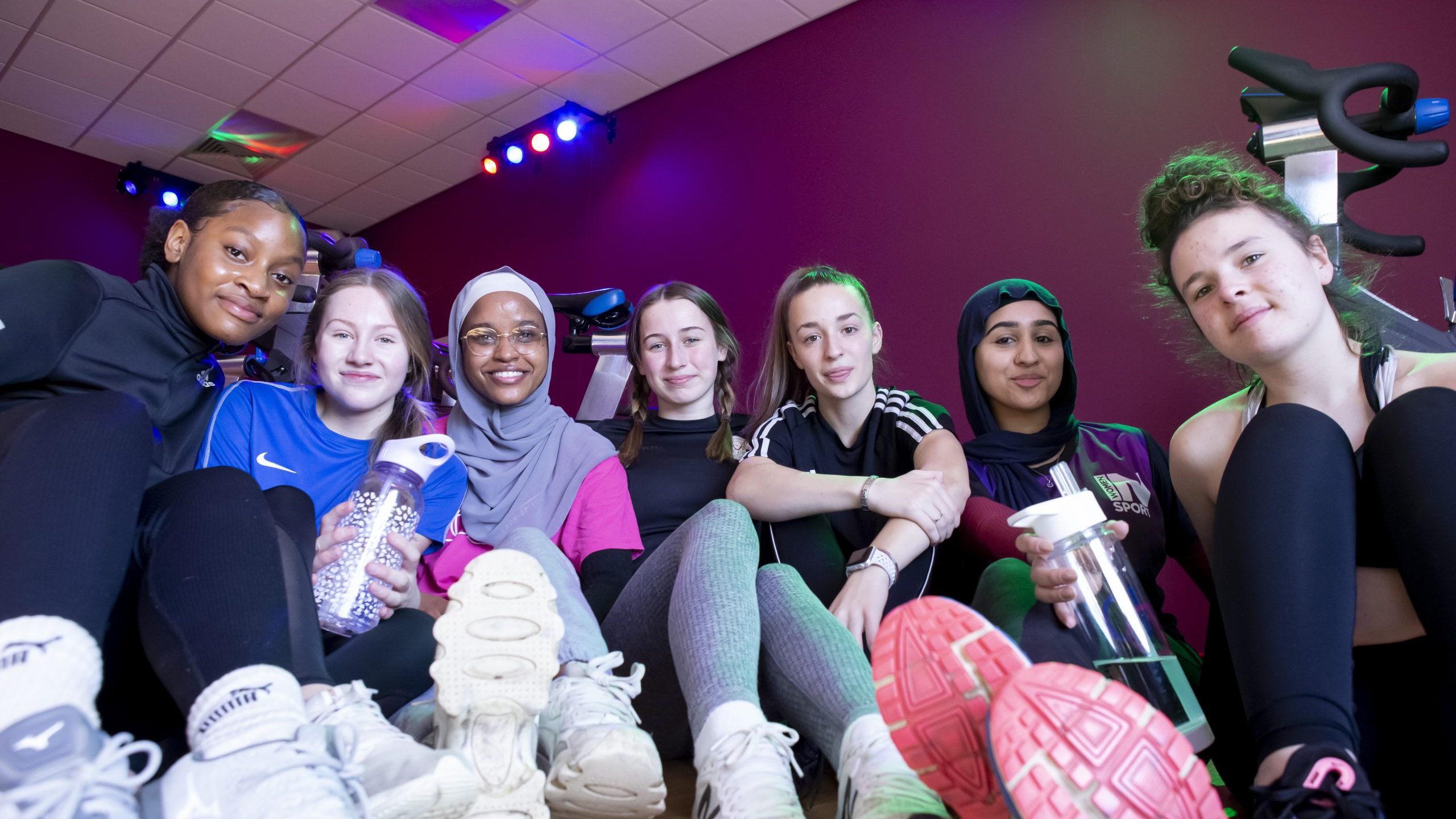 A group of girls sitting together in a leisure centre, smiling