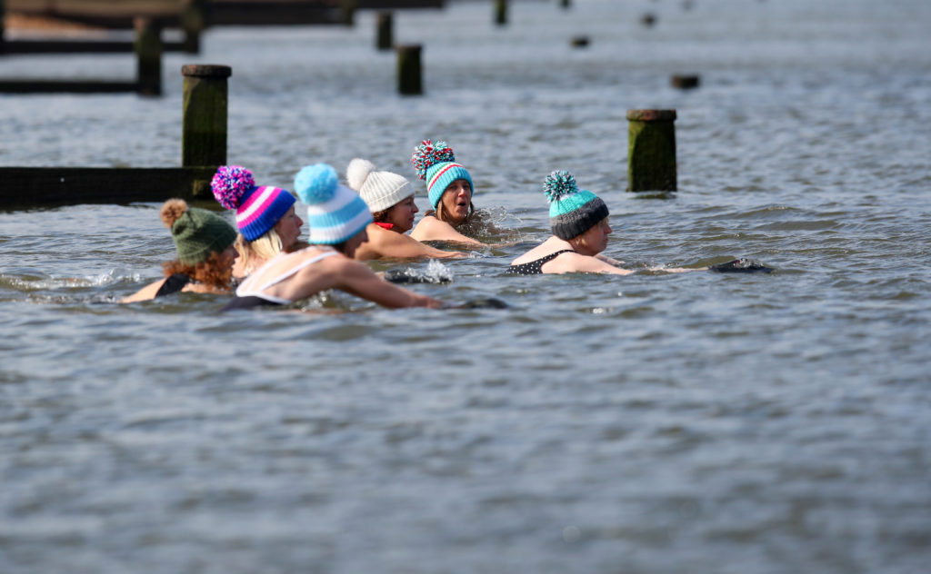 A group of women swimming in the sea with woolly hats to keep warm
