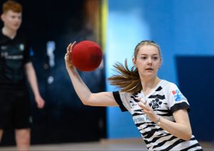 A young white woman playing dodgeball