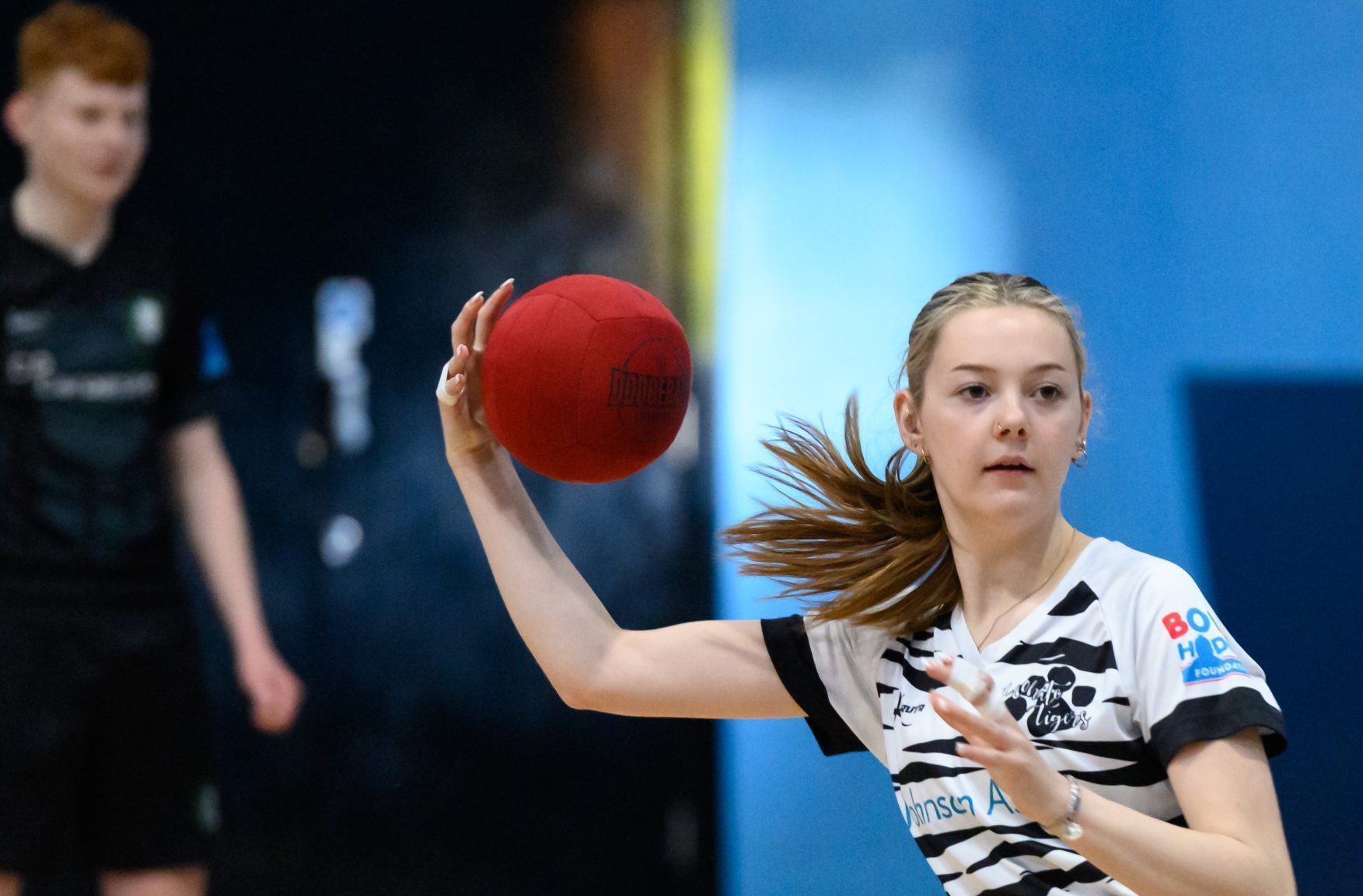 A young white woman playing dodgeball