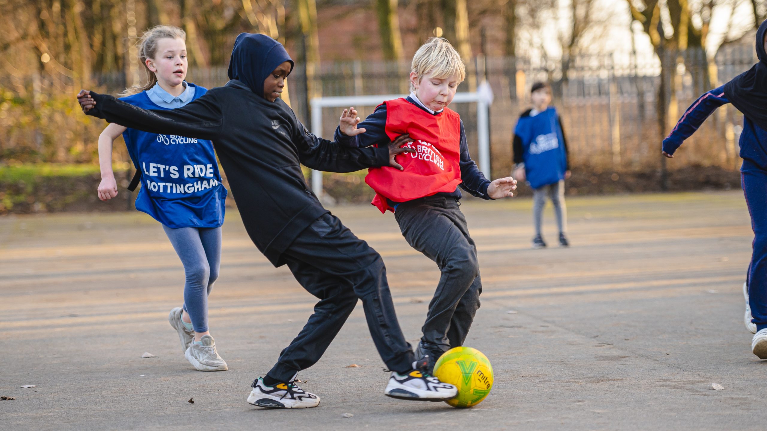 A young Muslim girl and young white boy playing football together at school