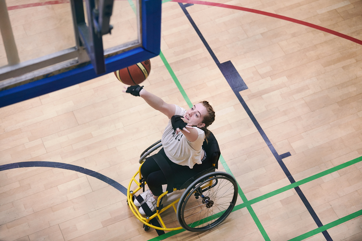 A white teenage playing wheelchair basketball
