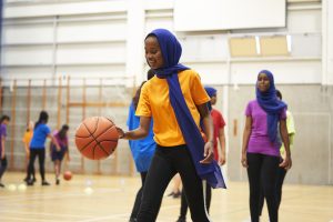 Muslim girl playing basketball at school