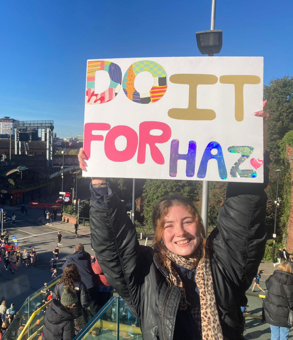 Harriet's friend supporting her family running the marathon with a sign that reads 
