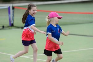 Primary girls playing tennis together