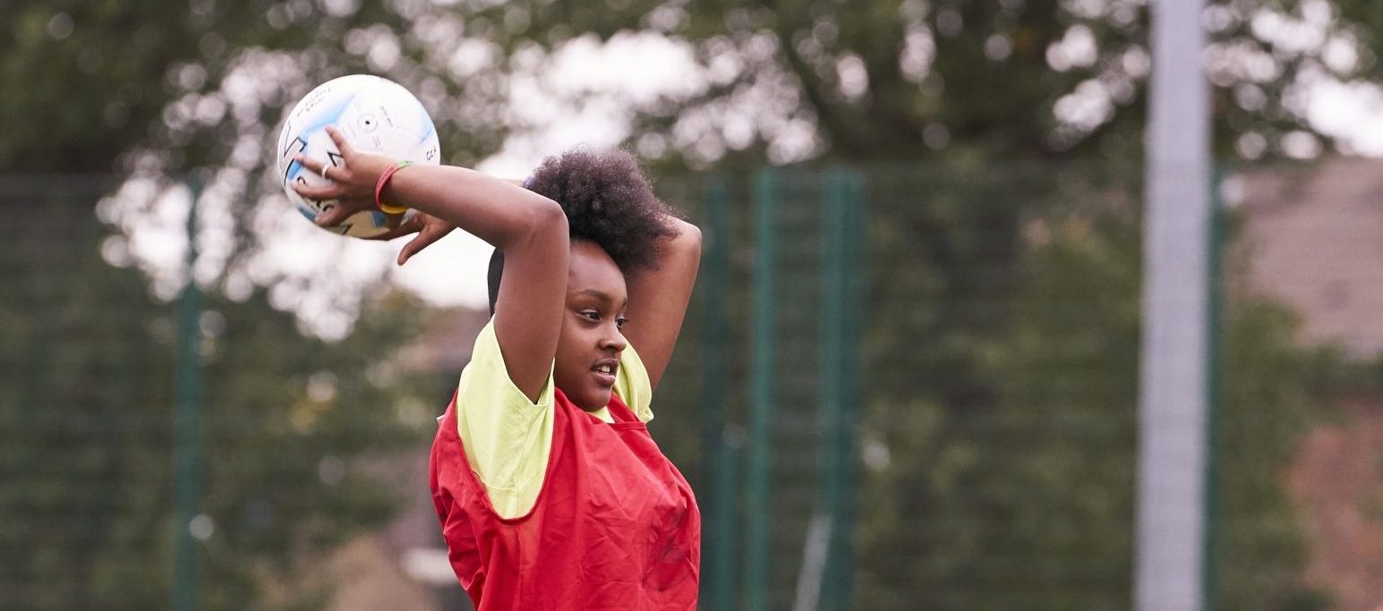 A teenage girl playing netball in PE