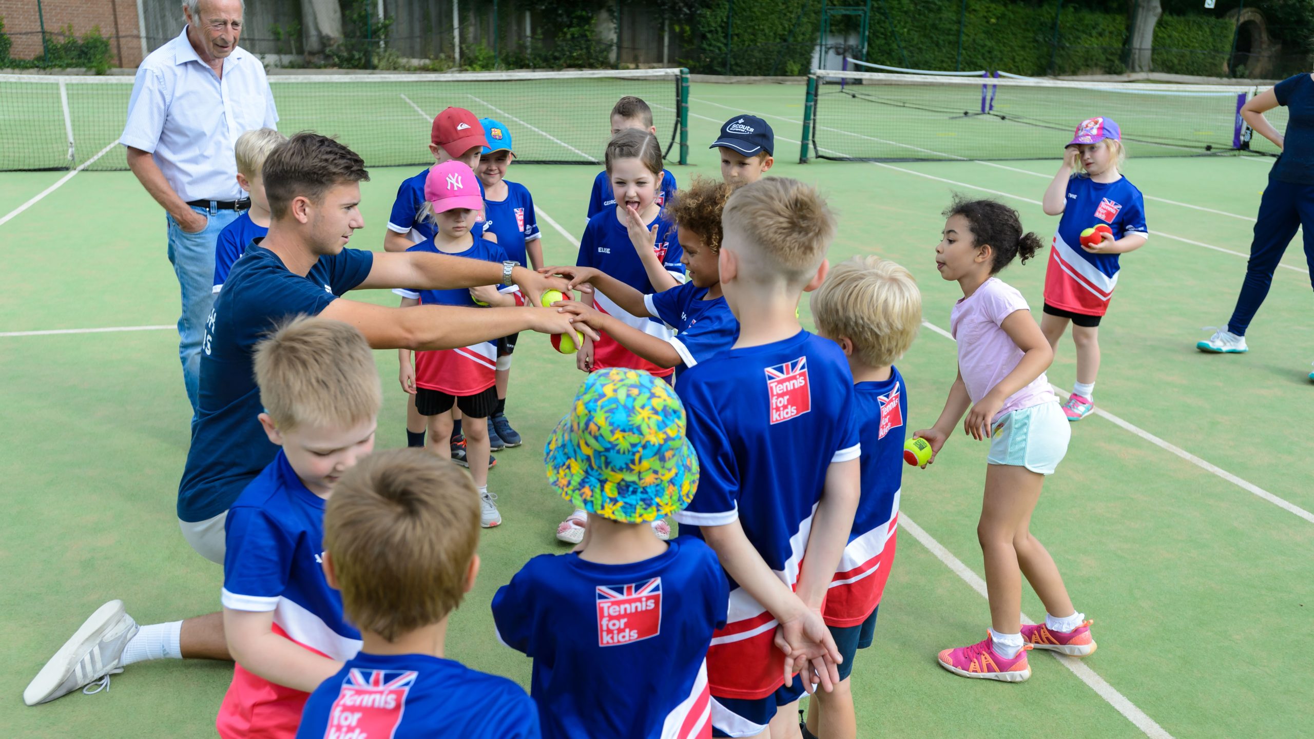 Tennis coach teaching young girls and boys