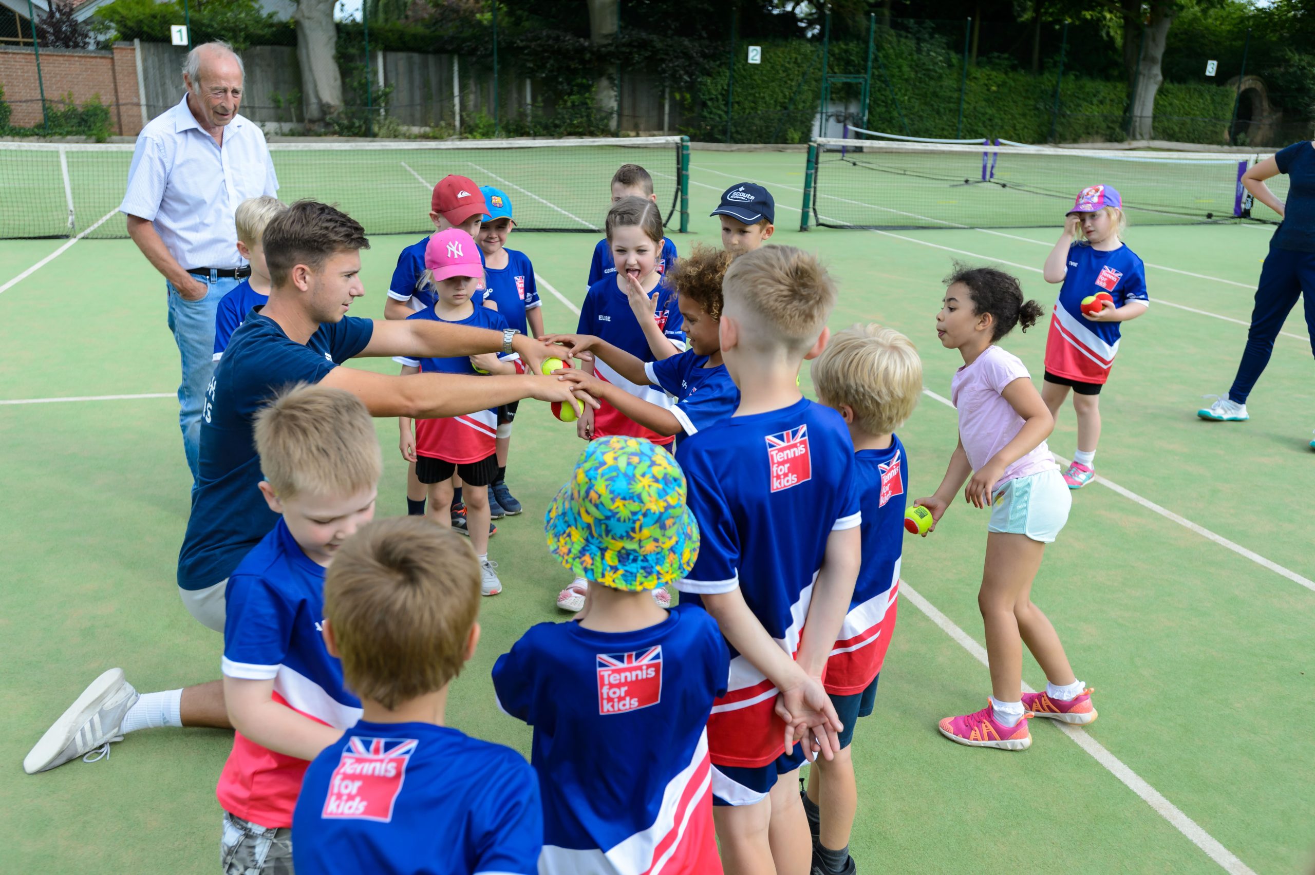 Tennis coach teaching young girls and boys
