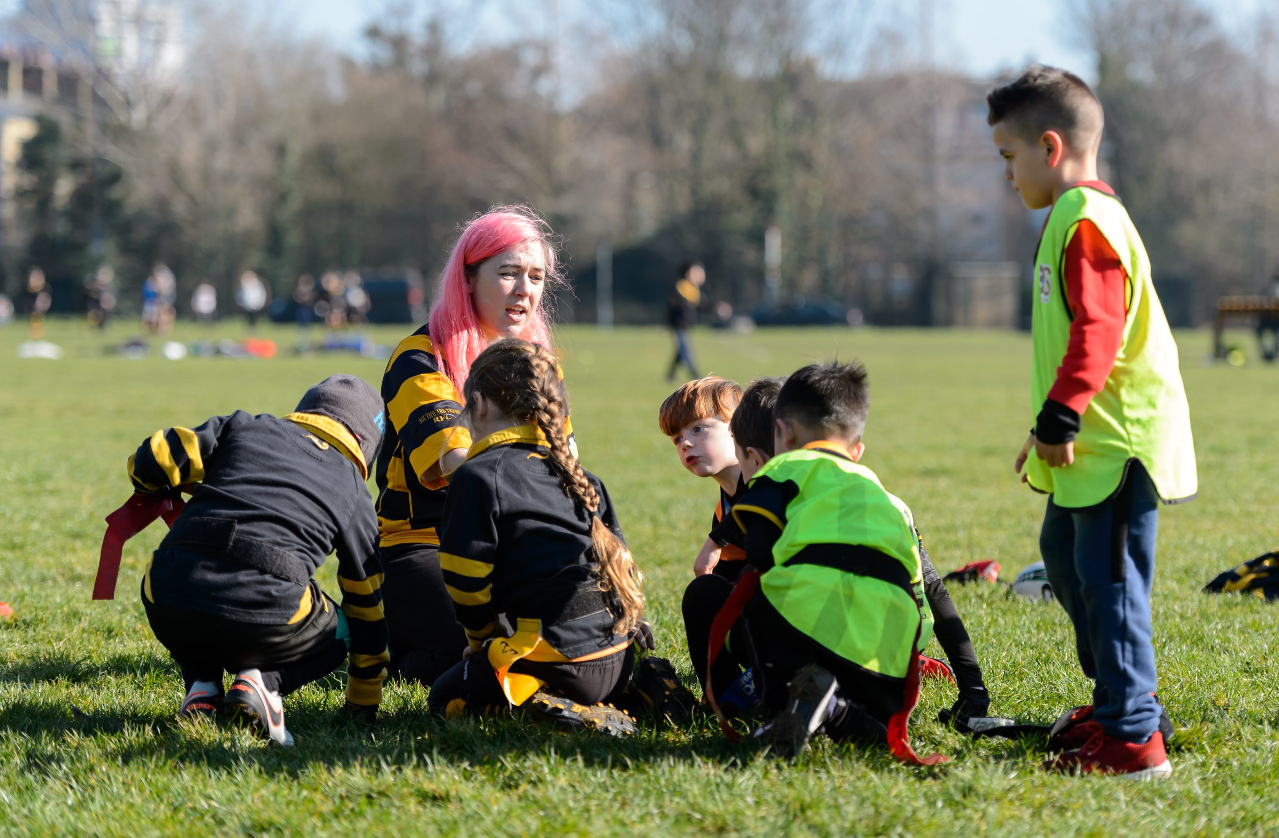 Woman coaching rugby to young boys and girls