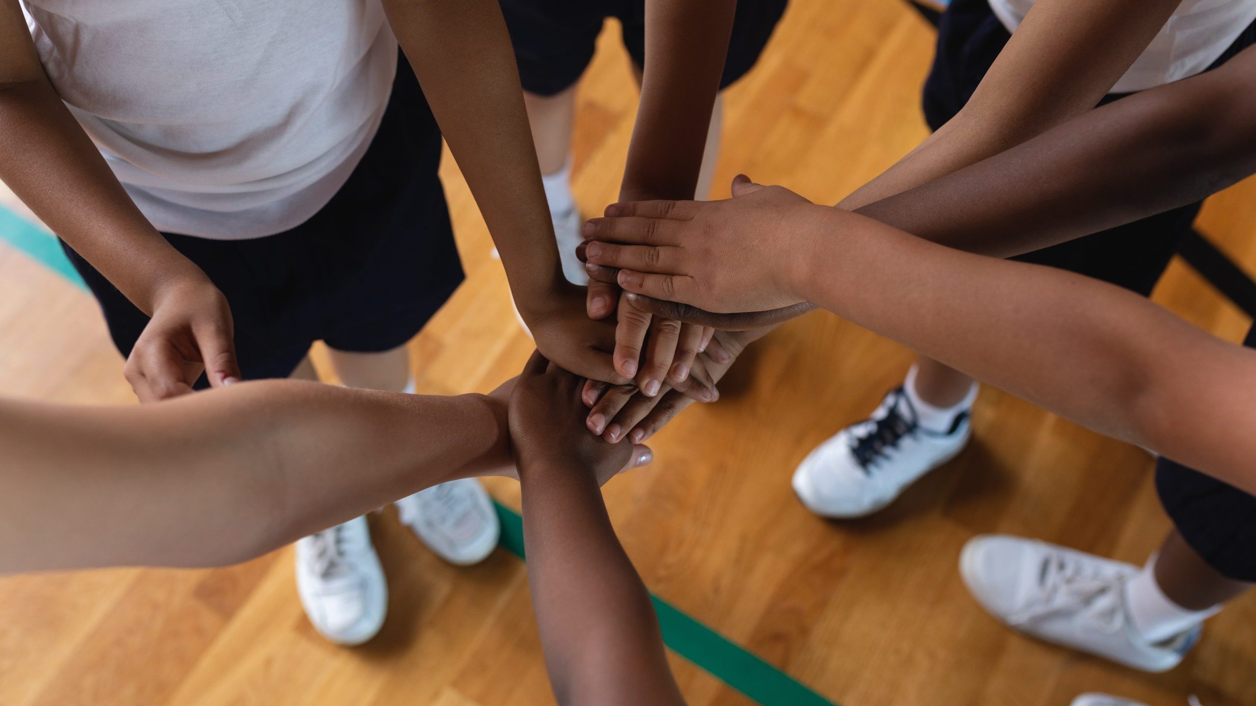 School children forming a hand stack in a pe lesson