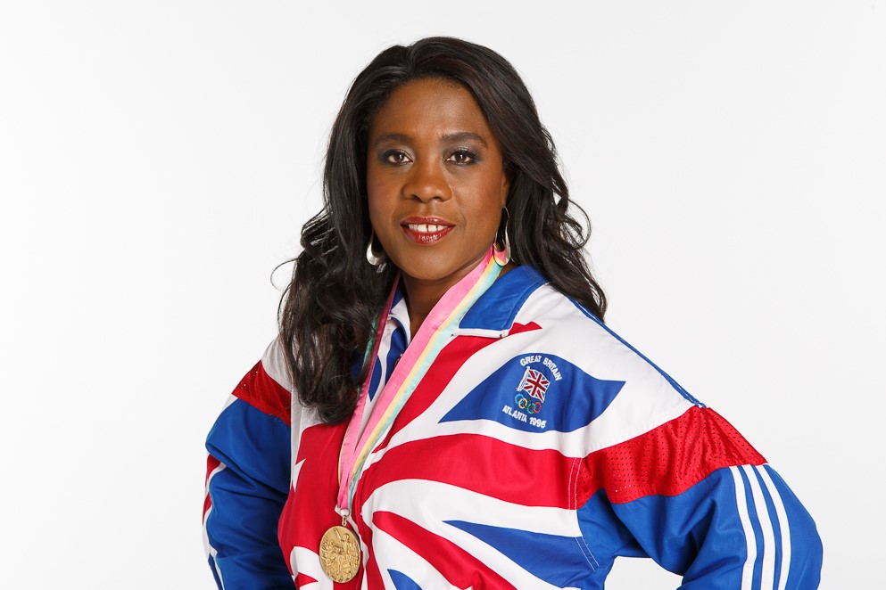 Tessa Sanderson wearing a top in the colours of the union flag with her Olympic gold medal around her neck