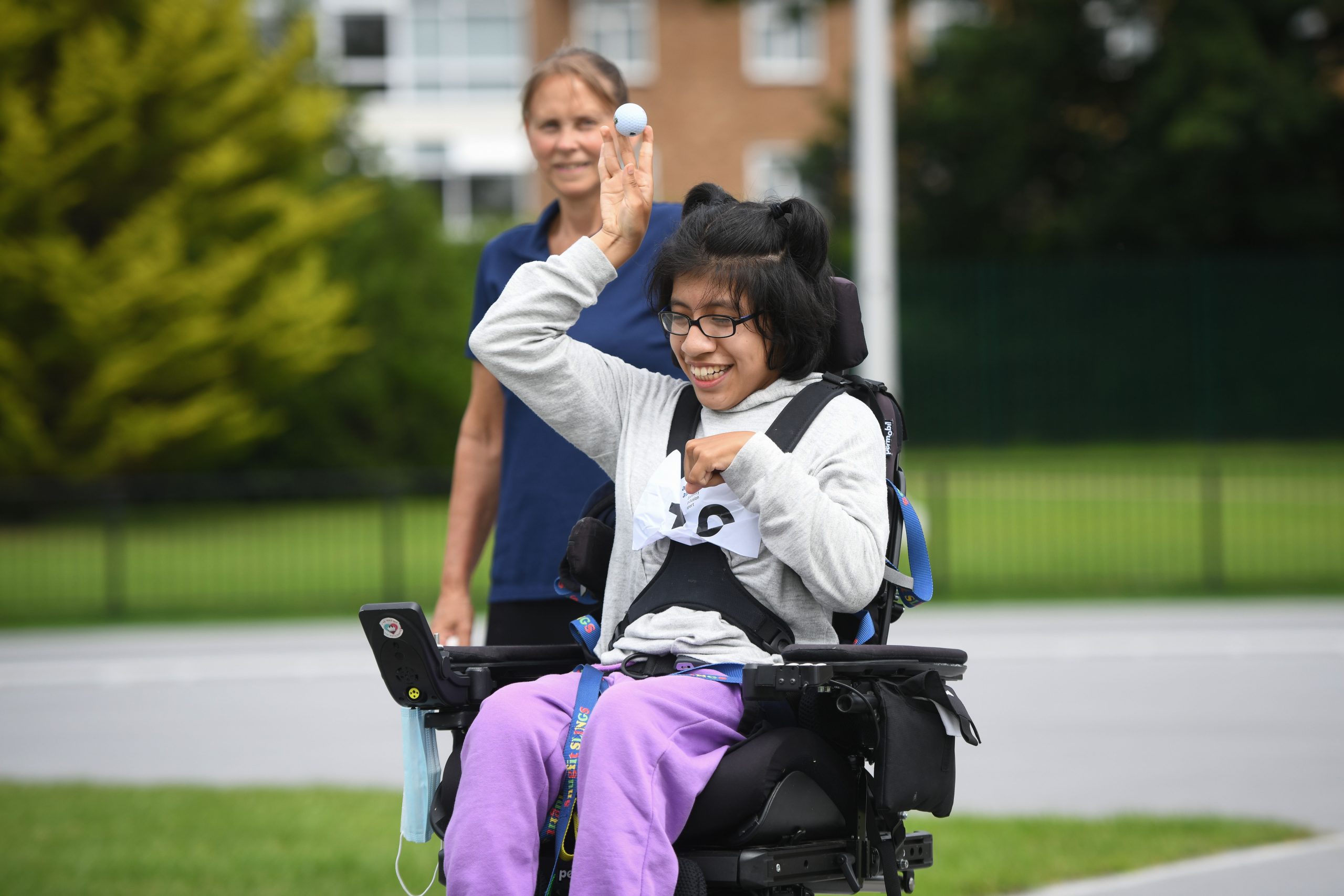 A young south asian girl in a wheelchair throwing a ball