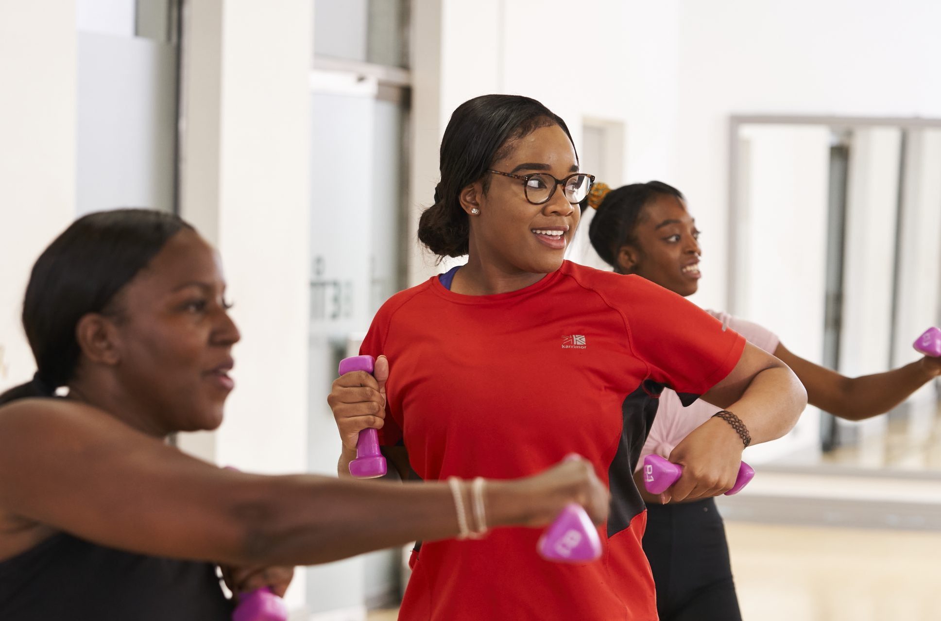 Three Black women aged 30-45 taking part in a fitness class