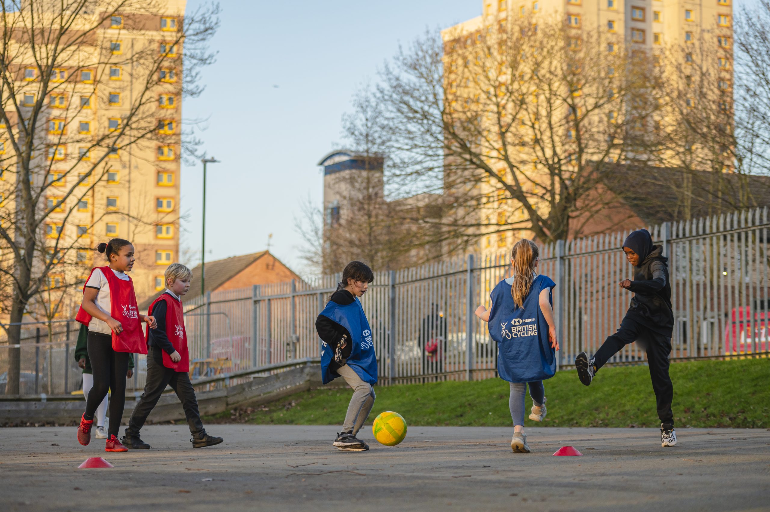A group of boys and girls playing football on the school playground