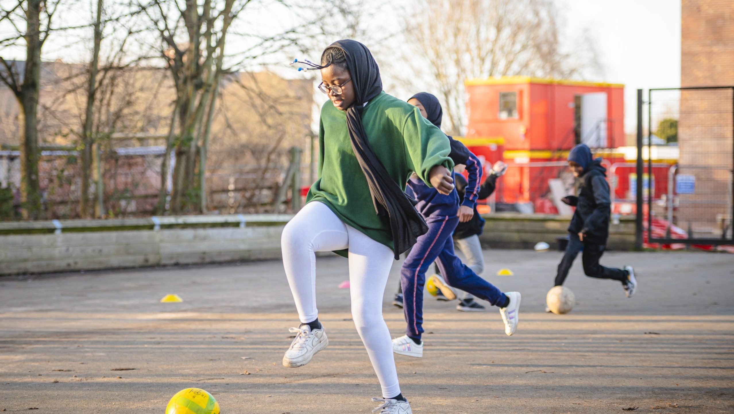 Black muslim girl playing football, smiling
