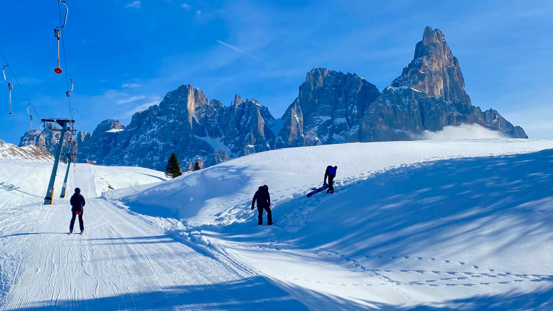 Three skiers and snowboarders on a snowy mountain ski slope
